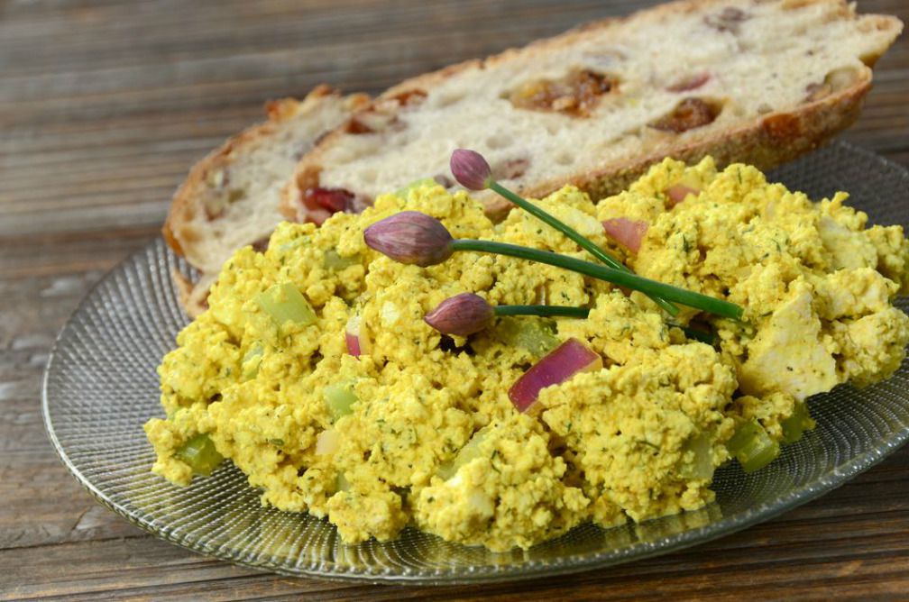 A plateful of vegetarian tofu "egg" salad with two slices of bread in the background