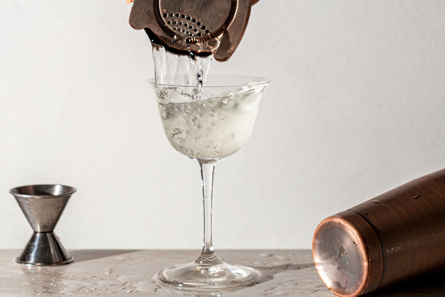 Straining the cocktail from the shaker into a glass