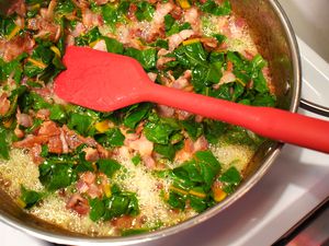 OXO spatula in a pan of sauteing greens and bacon