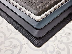 Closeup of a stack of anti-fatigue mats we recommend on a tiled floor